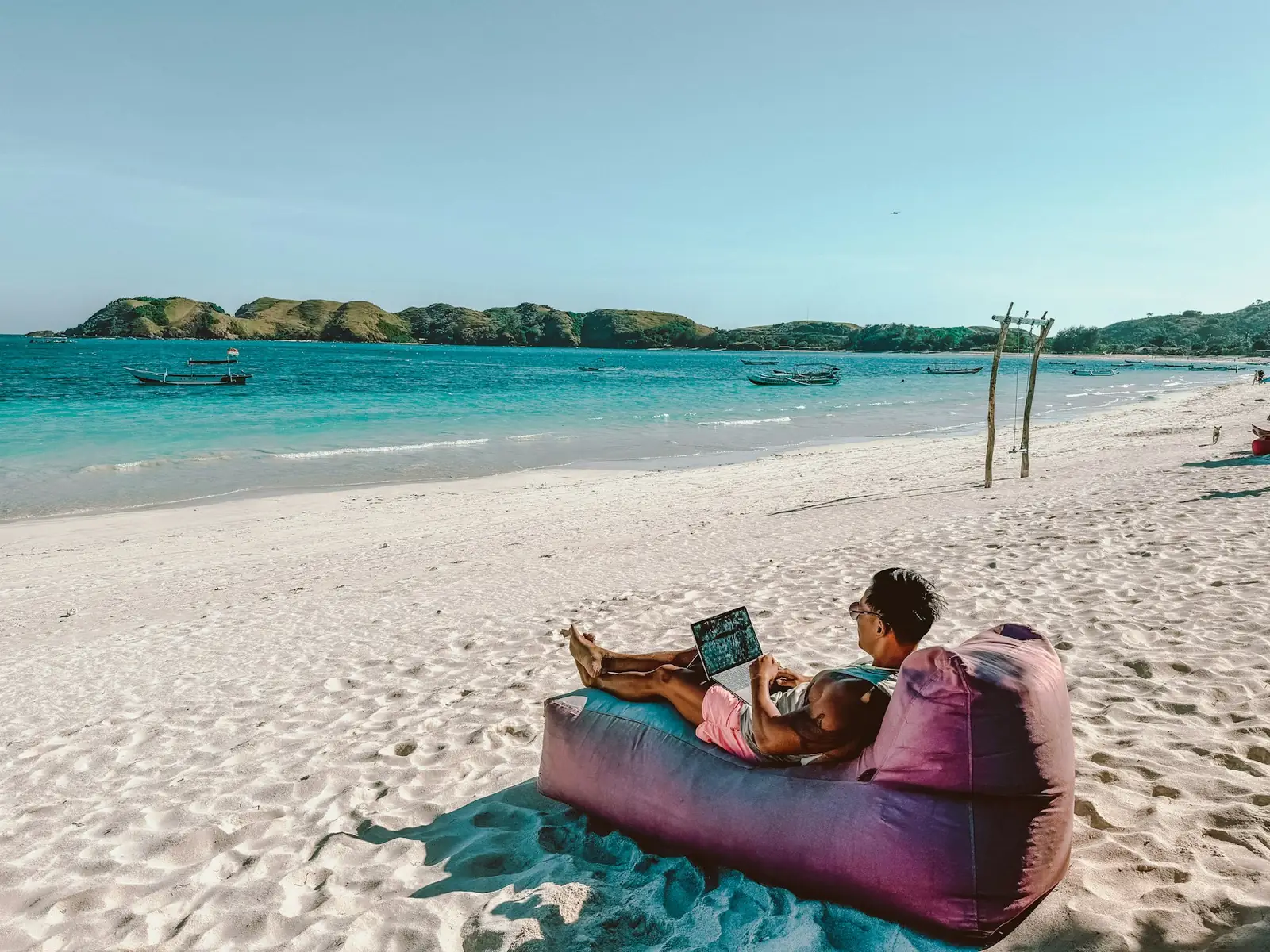Person working remotely on a laptop at the beach